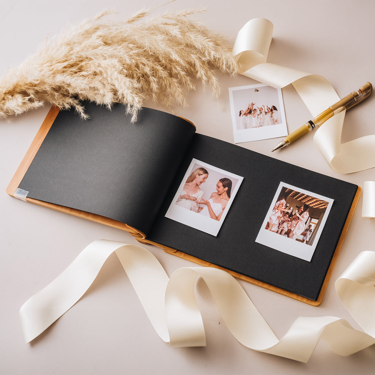 Open wooden guest book with black pages and instant photos