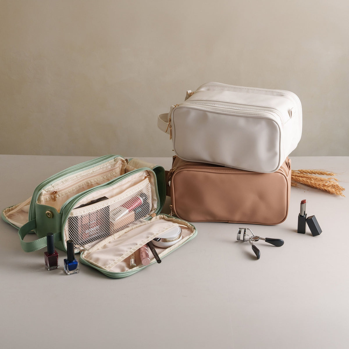 Open green cosmetic bag showing its compartments, with white and khaki bags