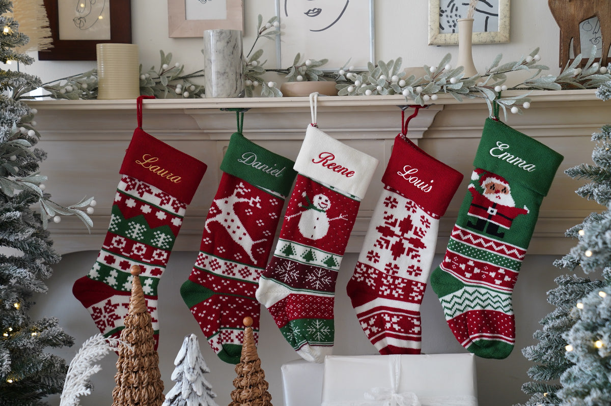 Five personalized knit Christmas stockings with embroidered names hanging on a mantel